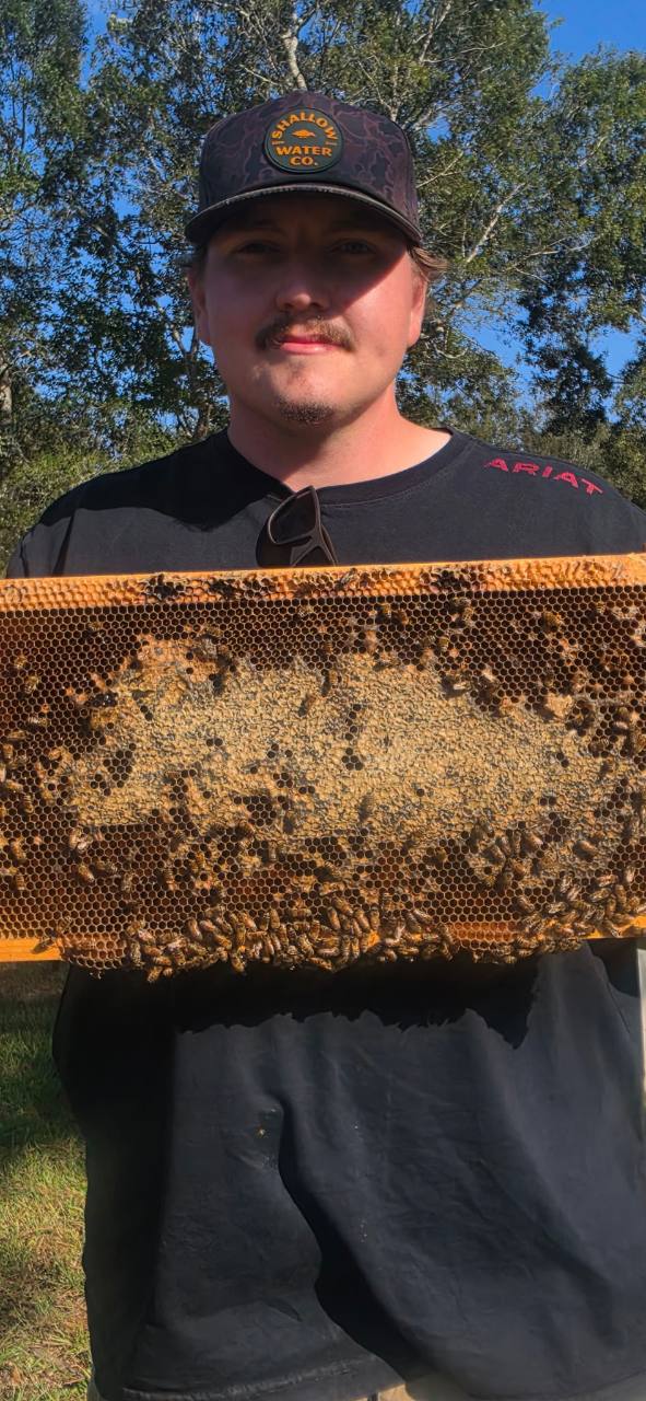 Blake McElwain holding a honey frame at Southern Drip Farms